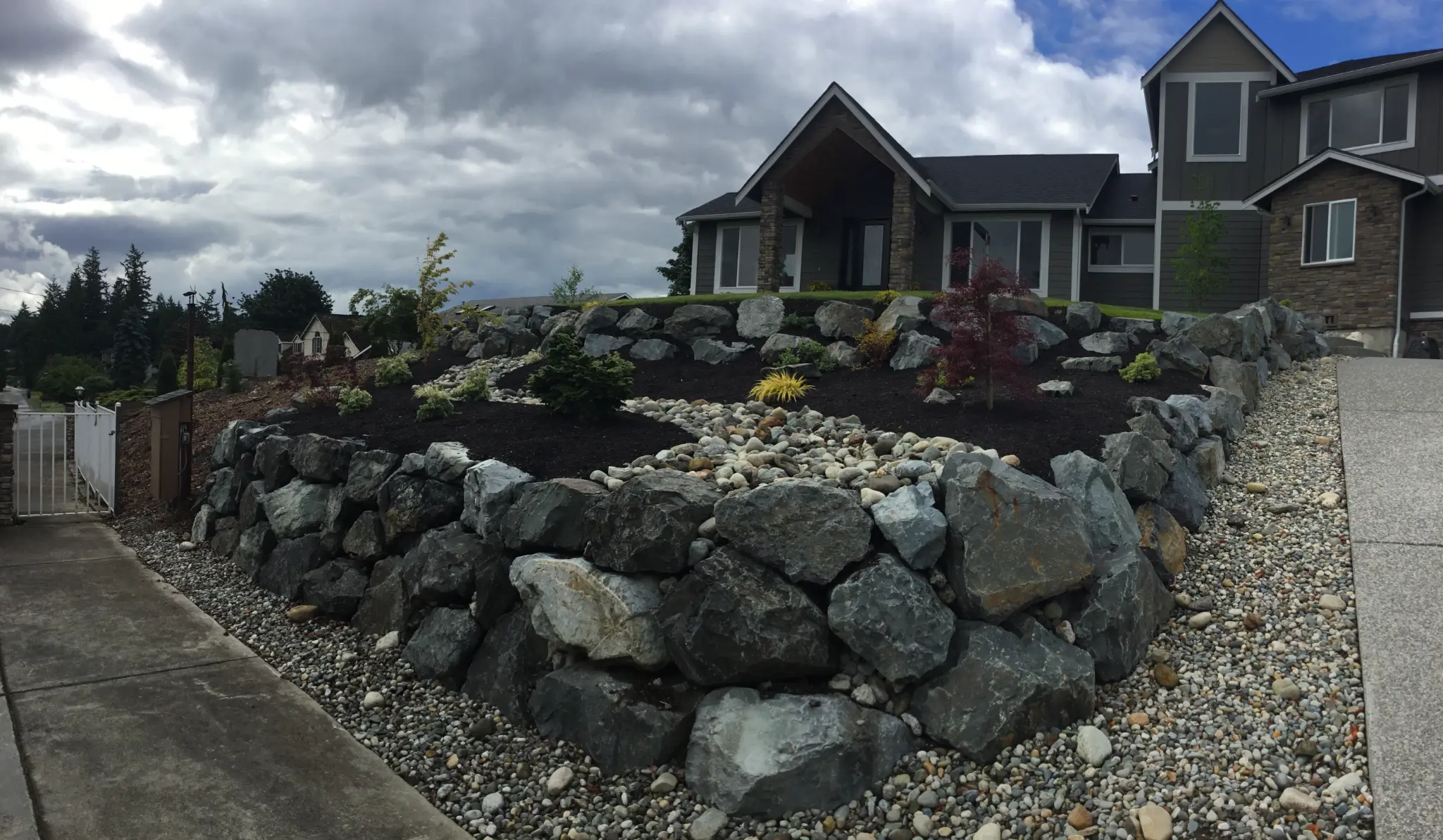 New construction front yard after — natural stone rockery and plantings