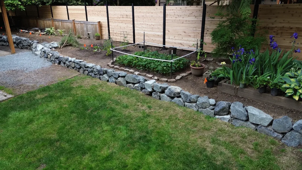 After — natural stone rockery lining the entire backyard edge
