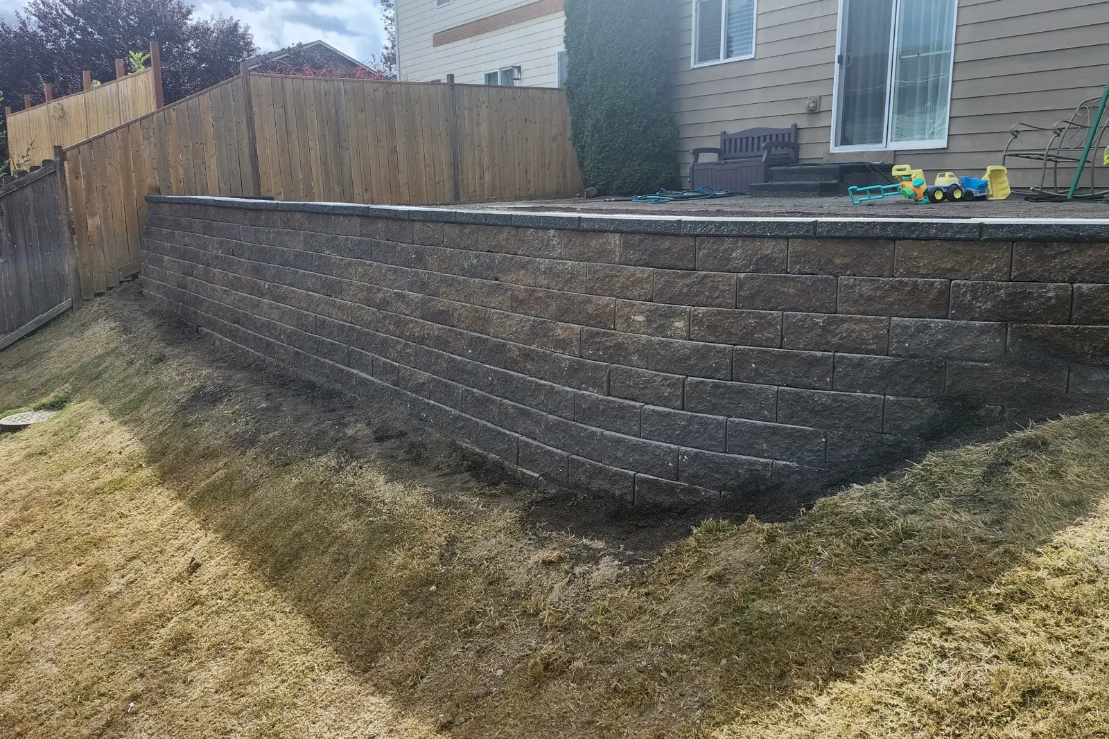 After — engineered concrete block retaining wall stabilizing the backyard slope