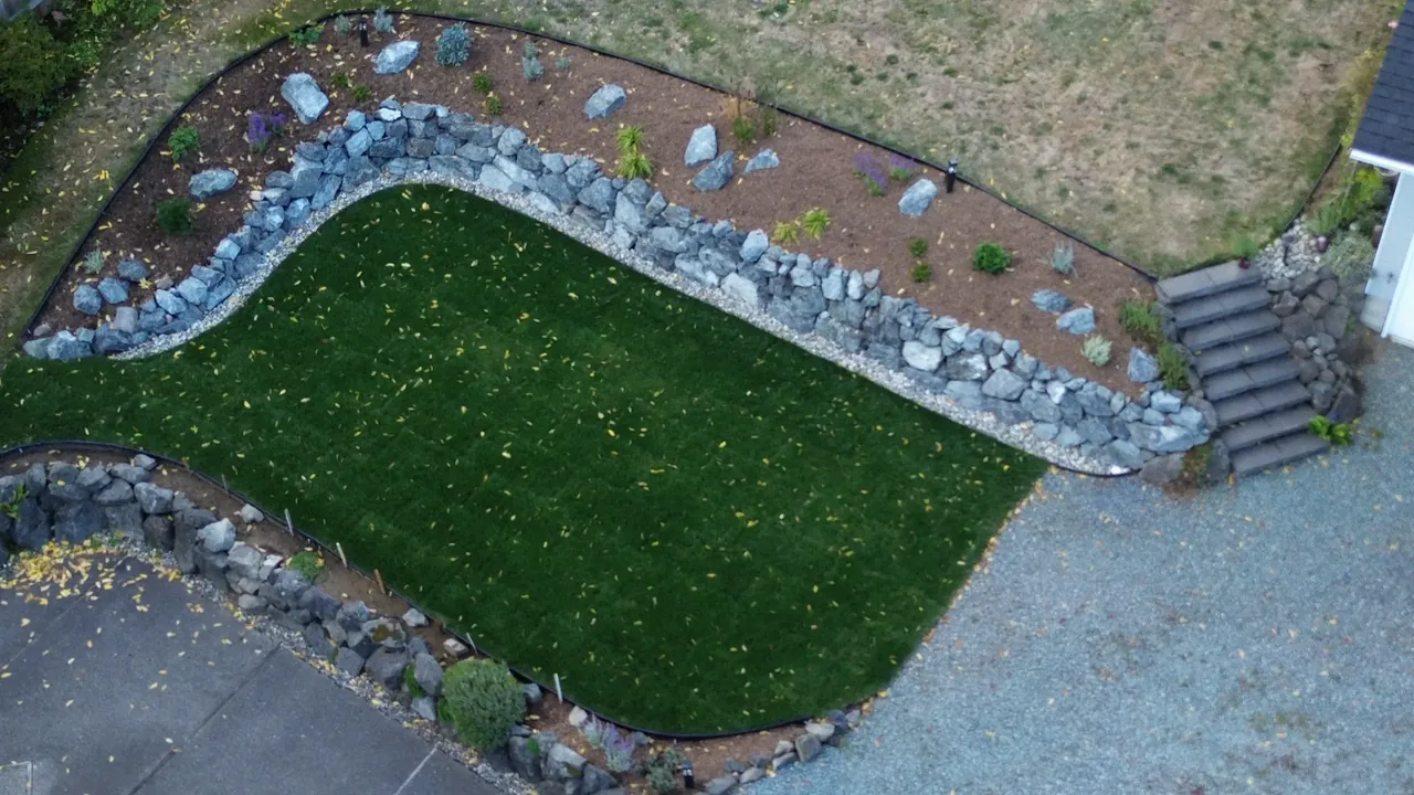 After — lush curved lawn with natural stone rockery border and steps