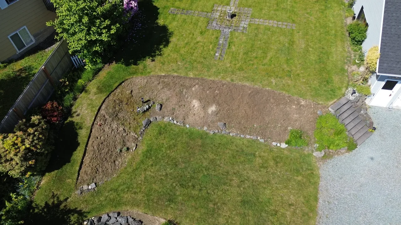 Before — bare excavated dirt, old small rocks, no wall