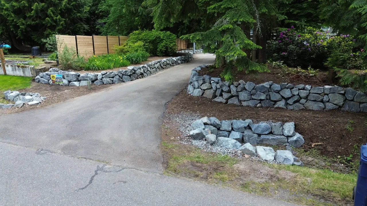 Driveway after — beautiful natural stone rockery lining both sides of the driveway