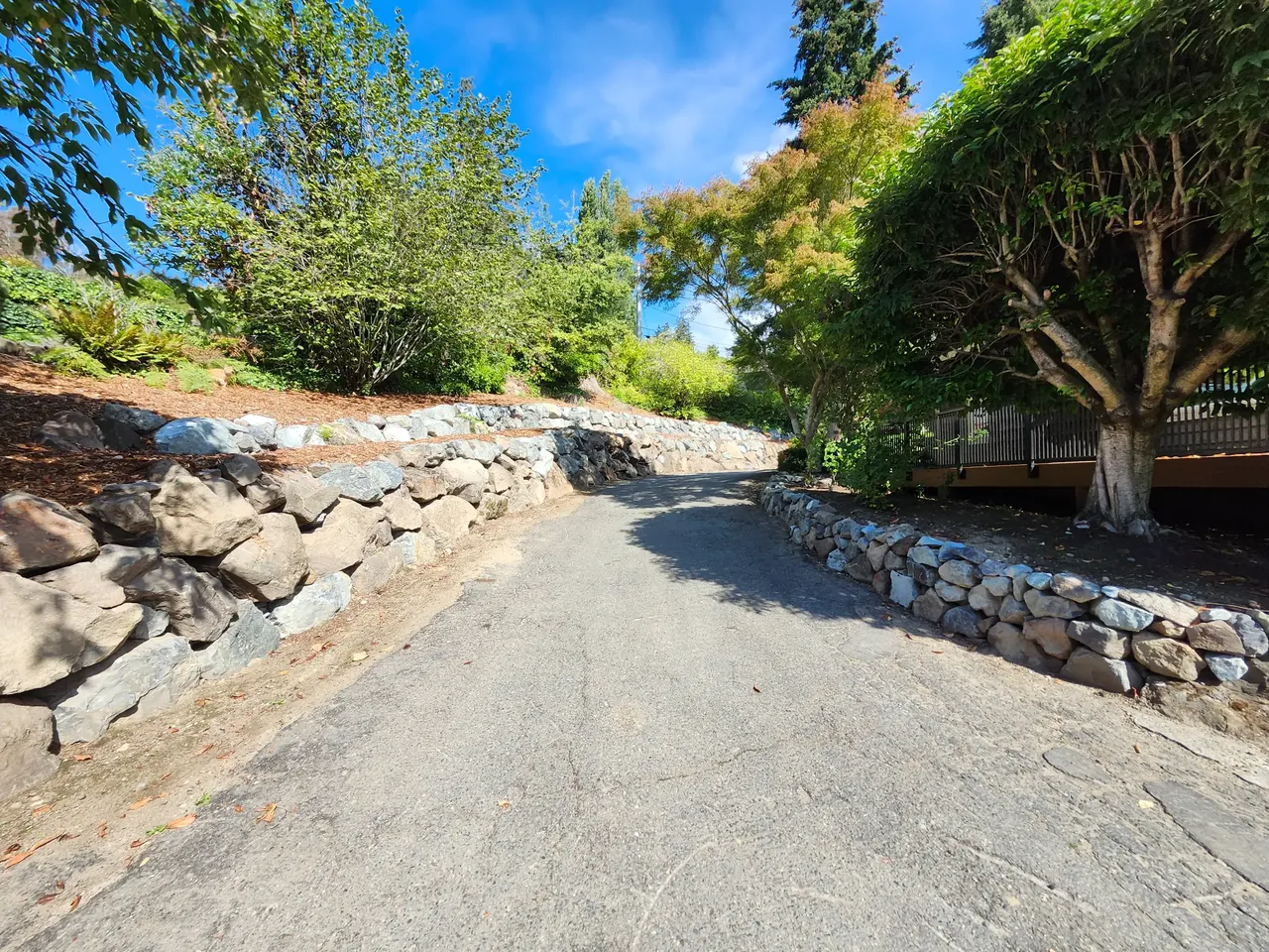 Driveway after — clean natural stone rockery walls on both sides