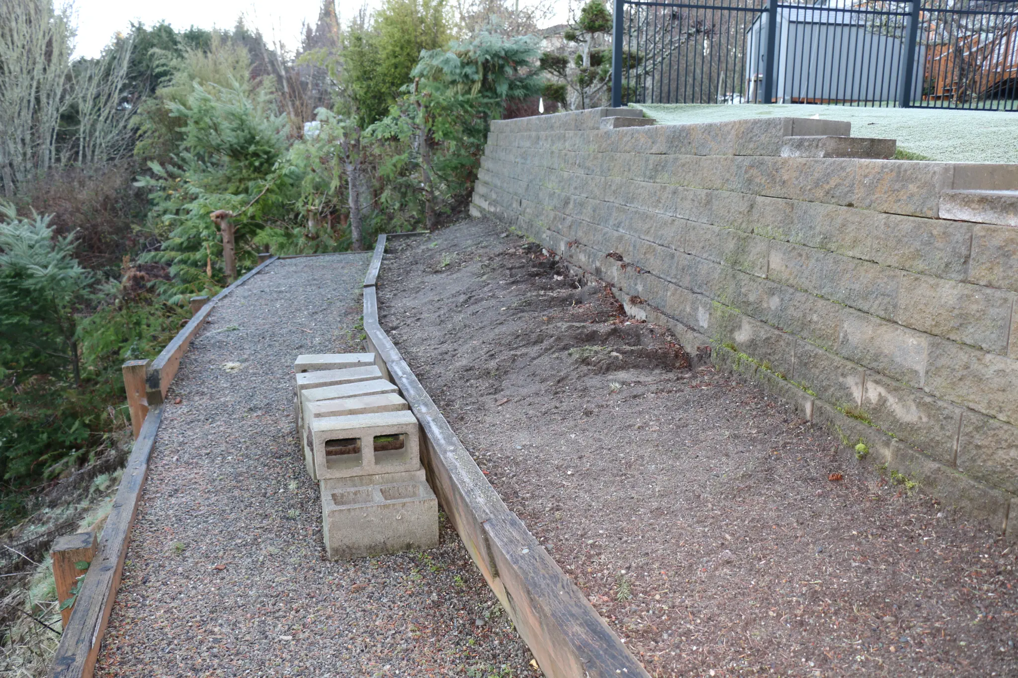 Before — aging concrete block retaining wall with gravel path